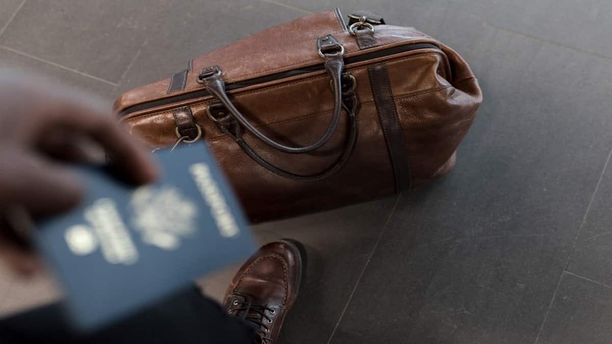 Man holding passport over weekend bag