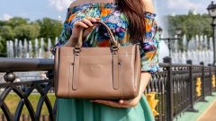 A woman holding a brown colored handbag